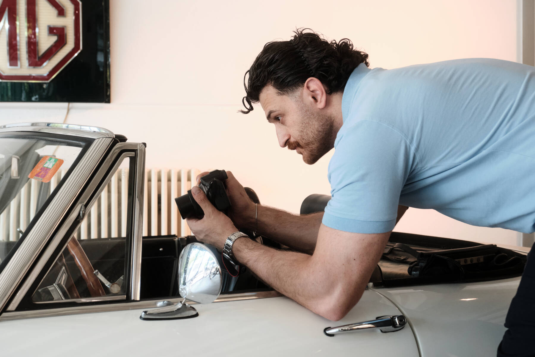 Ein Fotograf nimmt Detailaufnahmen eines klassischen Cabrio-Oldtimers im Studio auf.